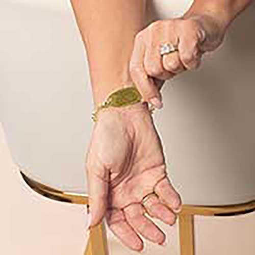 Woman displaying custom laser engraving on her gold toned medical ID tag.