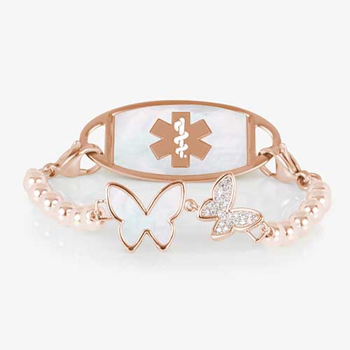 Serenity Stretch medical ID bracelet featuring rose gold filled beads and a double butterfly centerpiece adorned with crystal and mother of pearl inlay, attached to a rose gold medical ID tag featuring mother of pearl inlay and a rose gold caduceus.