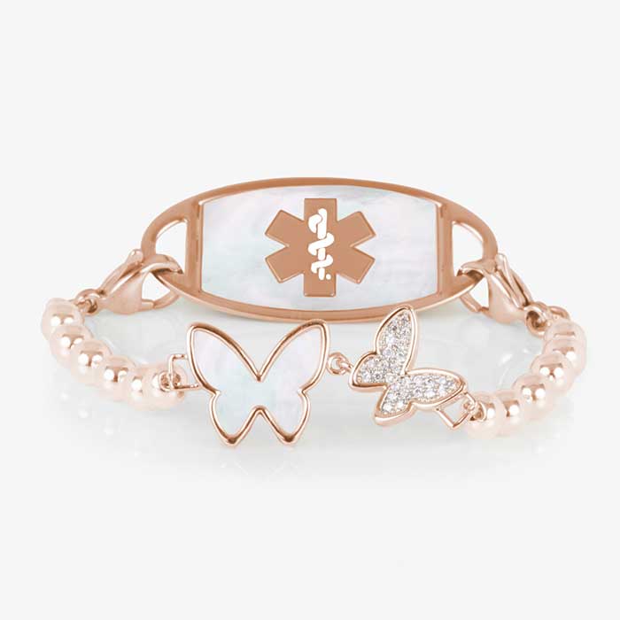Serenity Stretch medical ID bracelet featuring rose gold filled beads and a double butterfly centerpiece adorned with crystal and mother of pearl inlay, attached to a rose gold medical ID tag featuring mother of pearl inlay and a rose gold caduceus.