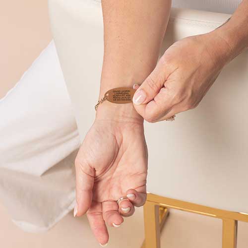 Woman displaying custom laser engraving on her rose gold toned medical ID tag.