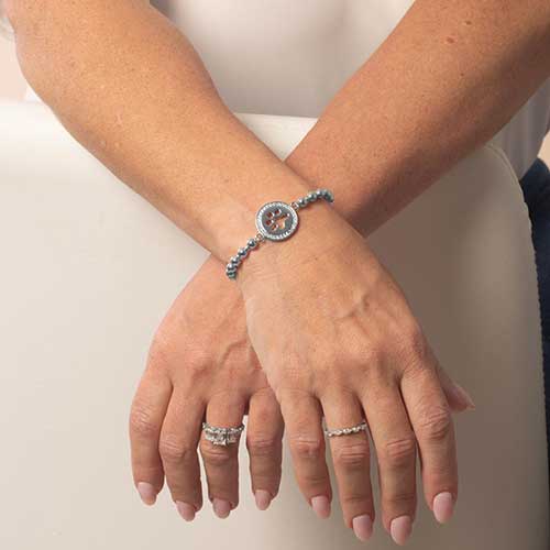 Model wearing the gold Sophie Stretch bracelet, showing the paw print charm centered on the top of the wrist.