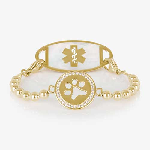 Gold beaded medical ID bracelet with a circular paw print charm accented by clear crystals, shown with a coordinating gold and mother-of-pearl medical ID tag featuring a gold medical symbol.