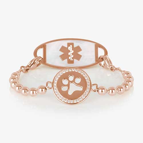 Rose gold beaded medical alert bracelet with a circular centerpiece featuring a cutout paw print and a border of clear crystals, displayed on a white background.