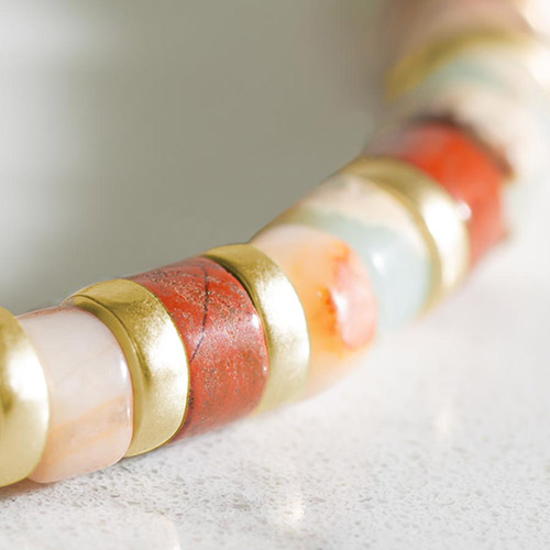 Close-up of Aris bracelet’s colorful stone heishi beads with brushed gold spacers in a repeating pattern.