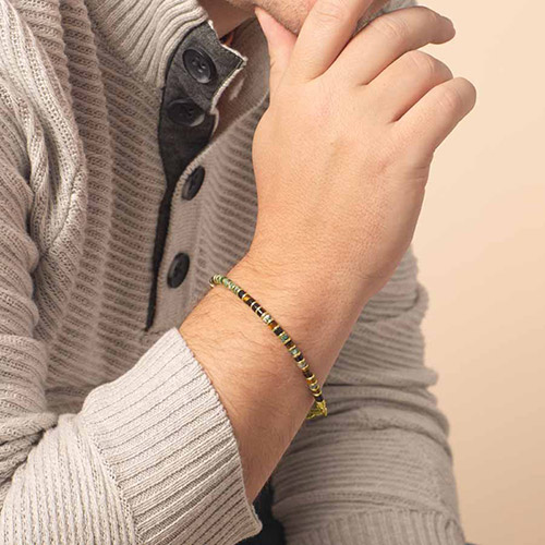 Close-up of a man wearing a stylish green and gold beaded medical alert bracelet, designed for discreet everyday wear with life-saving functionality.
