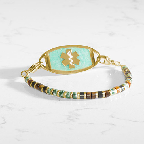 Gold, brown, and cream beaded stretch medical ID bracelet with amazonite tag in gold on marble background