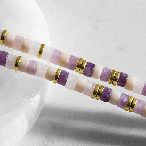 Close up of Beaded bracelet featuring gold tone, howlite, and Amethyst beads on a stretch bracelet.
