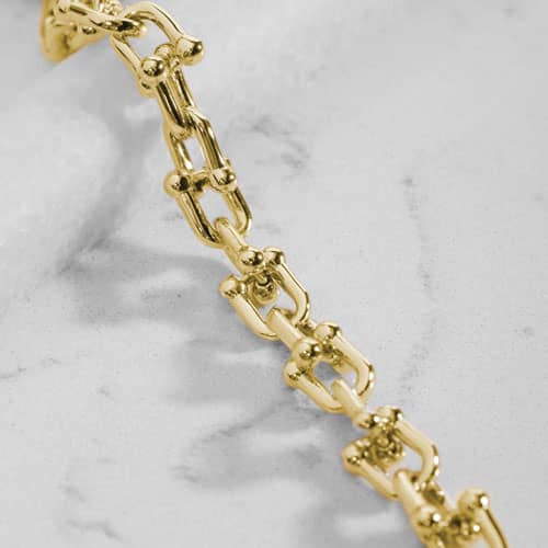 Close-up of polished gold-tone links with decorative barbell-style accents.