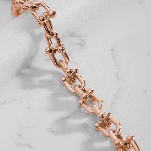 Close-up of polished rose gold-tone links with decorative barbell-style accents.