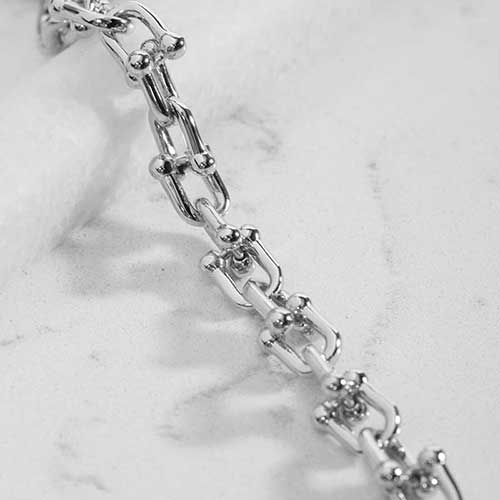 Close-up of polished silver-tone links with decorative barbell-style accents.