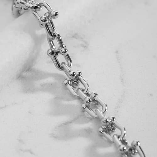 Close-up of polished silver-tone links with decorative barbell-style accents.