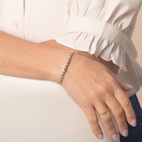 Woman wearing the Stella Gold bracelet, featuring a sleek row of sparkling clear stones in an elegant interchangeable design.