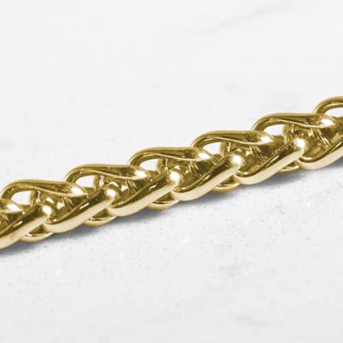 Close-up of the polished interwoven wheat chain links on a gold-tone medical ID bracelet.