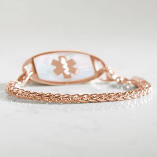 Rose gold wheat chain medical ID bracelet photographed on a white marble surface.