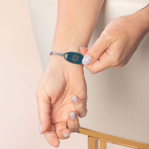 Person revealing the deep blue medical ID tag and Star of Life on a bracelet worn at the wrist.