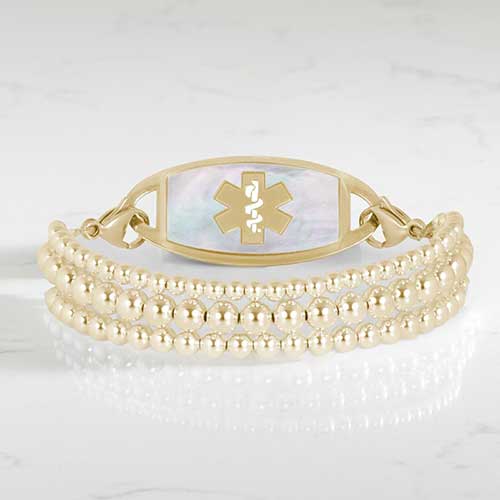 Gold Tilly medical ID bracelet featuring layered beaded strands and a mother-of-pearl Star of Life tag.