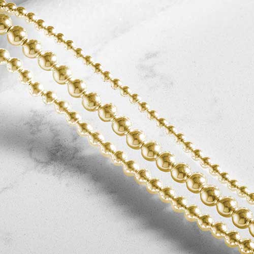 Close-up of the Tilly bracelet’s three strands of polished gold beads.