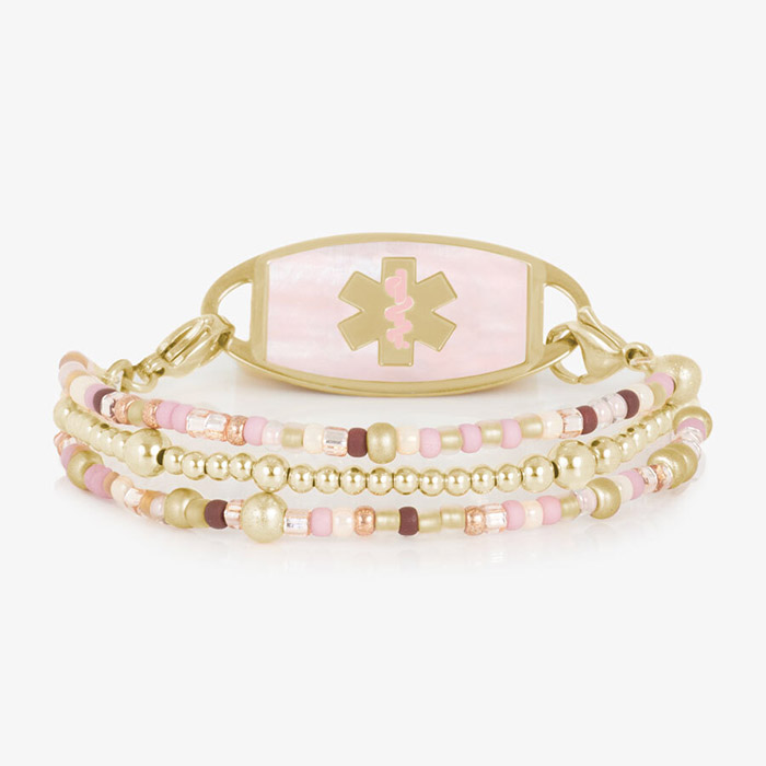 Three-strand beaded medical ID bracelet with gold-tone accents, pink and cream beads, and a pink inlay tag with medical symbol.