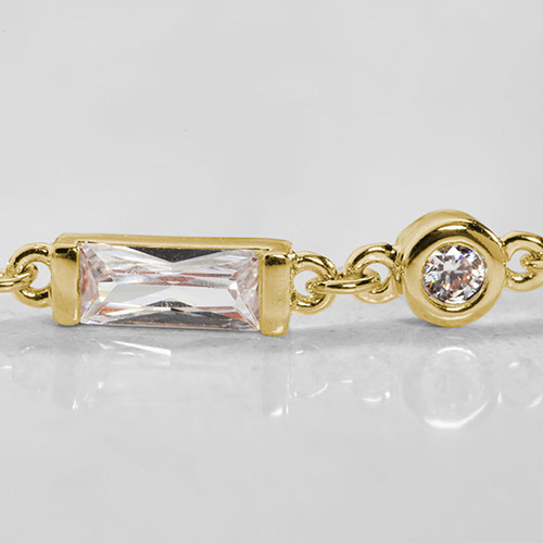 Close-up of the gold-plated bracelet chain showing a rectangular crystal and round bezel-set crystal links with a bright, faceted finish.