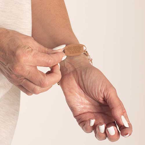 Woman showing premium laser engraving on rose tonestainless steel medical ID tag.