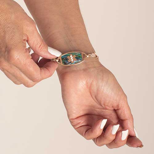 Woman showing rose tone stainless steel medical ID tag with abalone inlay and rose tone medical symbol.