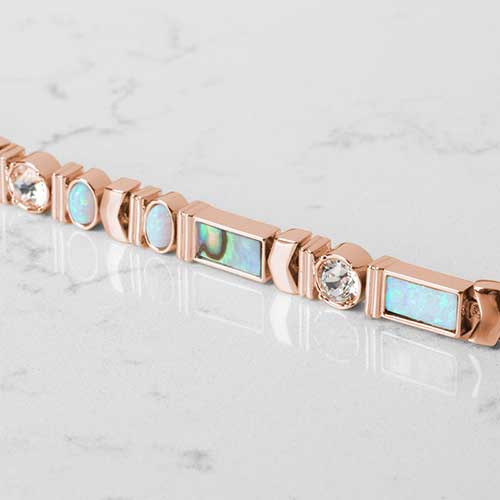Close Up Of rose tone herringbone medical ID bracelet with abalone, opal, crystal, and moon stone accents paired with abalone medical ID tag.