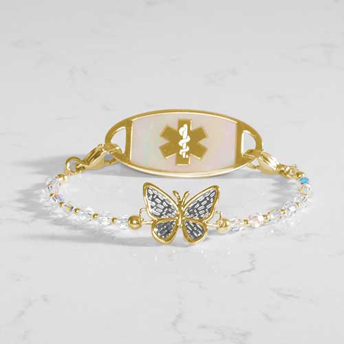 12k gold plated medical ID bracelet featuring iridescent beads surronding a gold plated butterfly centerpiece with decorative silver details, attached to a gold tone mother of pearl medical ID.