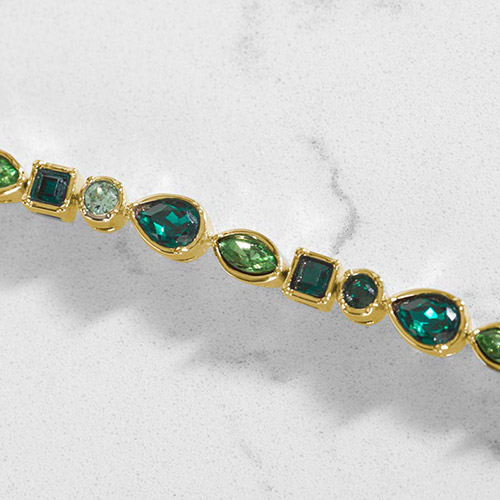 Close-up of bracelet details on Kate Medical Alert Bracelet, highlighting emerald and peridot cubic zirconia in luxe gold bezels