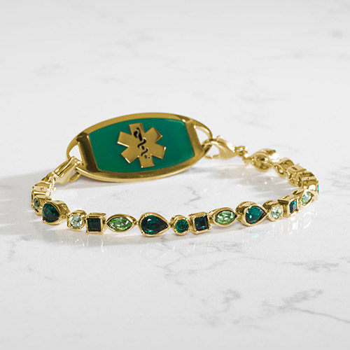 Kate Medical ID Tennis Bracelet in 12k Gold Plate, shown on wrist with Lauren’s Hope medical ID tag, showcasing radiant green crystals