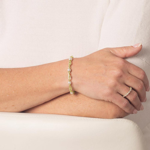 Woman wearing Bridle links in gold paired with luminous faux pearls and attached to a gold medical ID tag with inlaid mother of pearl.