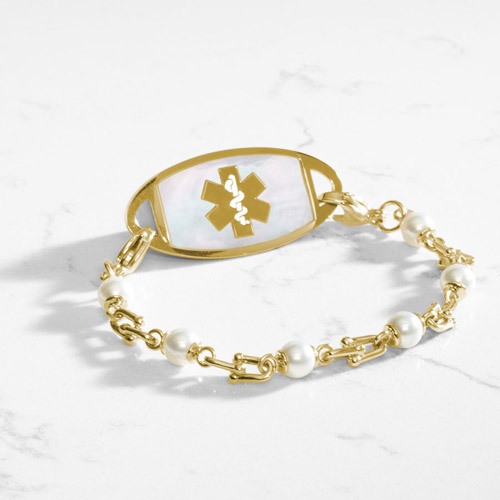Bridle links in gold paired with luminous faux pearls and attached to a gold medical ID tag with inlaid mother of pearl.