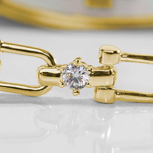 Close-up of a sparkling cubic zirconia set in a polished gold link of a women’s medical ID bracelet, showing fine detail and craftsmanship.