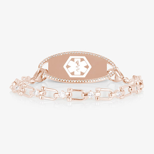 Close-up of the Diana medical ID bracelet in rose gold with CZ accents and an oval, crystal-framed ID tag engraved with the medical caduceus symbol.