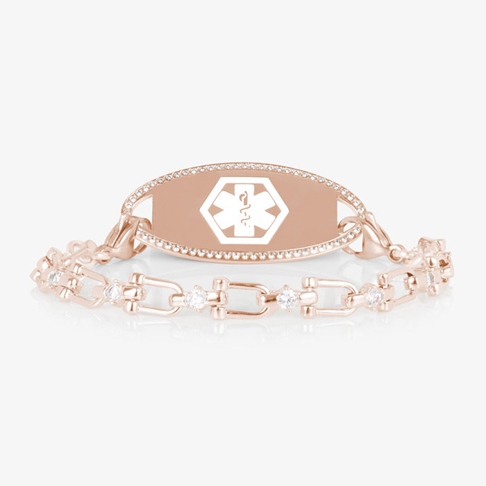Close-up of the Diana medical ID bracelet in rose gold with CZ accents and an oval, crystal-framed ID tag engraved with the medical caduceus symbol.