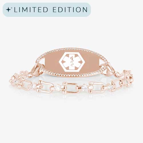 Close-up of the Diana medical ID bracelet in rose gold with CZ accents and an oval, crystal-framed ID tag engraved with the medical caduceus symbol.