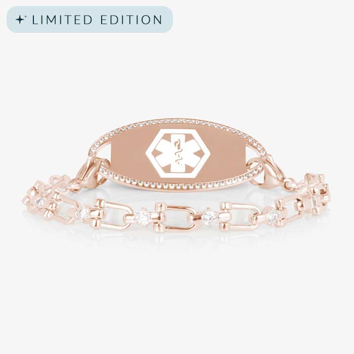 Close-up of the Diana medical ID bracelet in rose gold with CZ accents and an oval, crystal-framed ID tag engraved with the medical caduceus symbol.