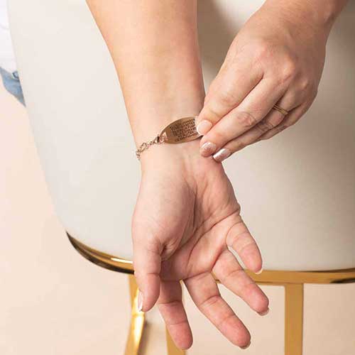 Woman wearing the Diana rose gold medical ID bracelet, showing custom engraved emergency medical information on the back of the ID tag.