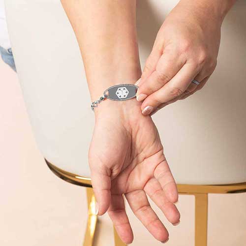 Woman wearing a silver Diana CZ medical alert bracelet with medical symbol visible, styled for everyday wear.