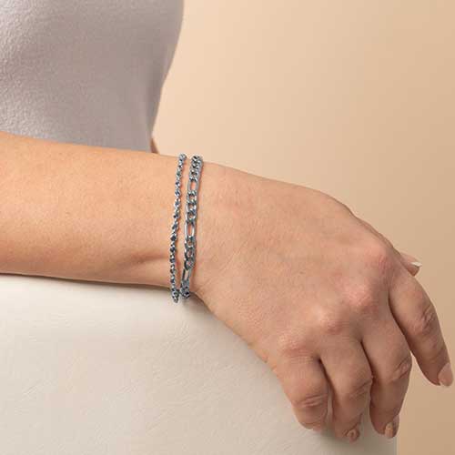 Woman wearing a dual chain, featuring blue crystal accents and a figaro chain.