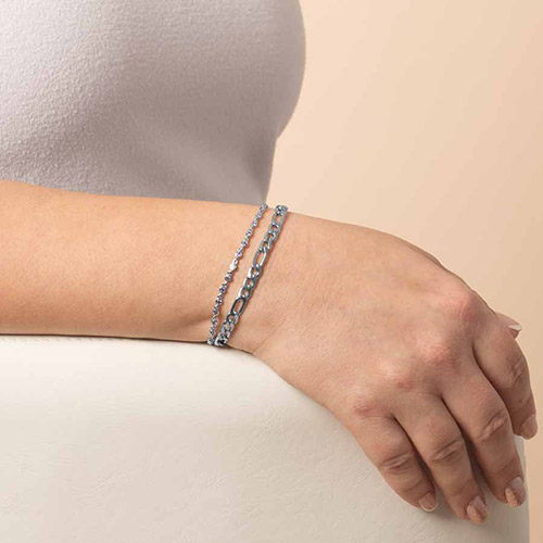 Side view of a person wearing a double-strand chain bracelet in silver and lavender tones, styled on the wrist against a soft neutral background.