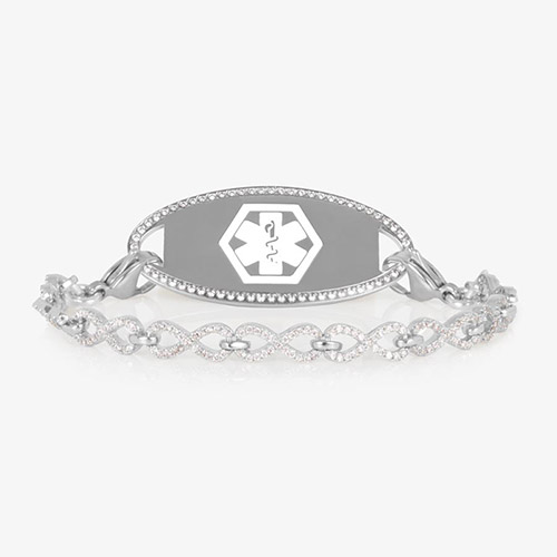 Silver medical ID bracelet with an infinity-link chain encrusted in clear CZs, paired with a matching oval tag outlined in crystals.