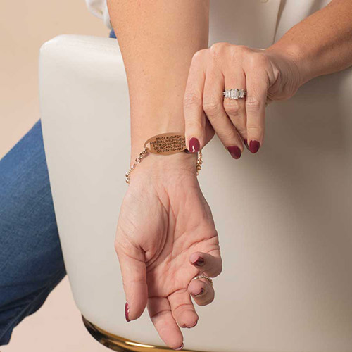 Woman’s wrist displaying the engraved medical ID tag on the Harper Rose bracelet, featuring rose gold accents and legible emergency information.