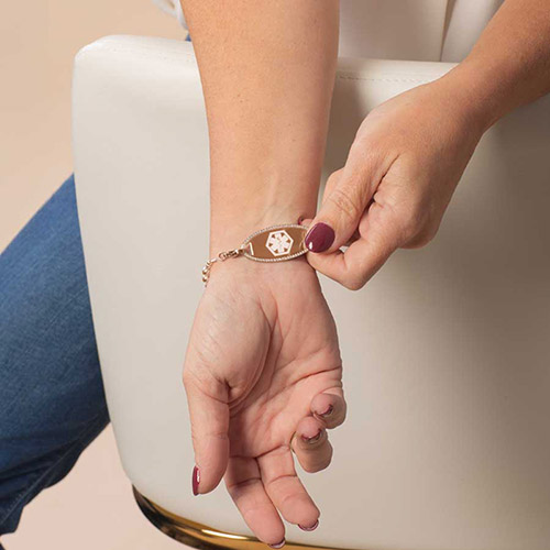 Close-up of the Harper Rose bracelet’s medical ID tag on the wrist, featuring a rose gold plate with a prominent white medical caduceus symbol.