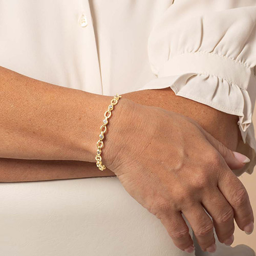 Gold version of the medical ID bracelet shown on a woman's wrist.
