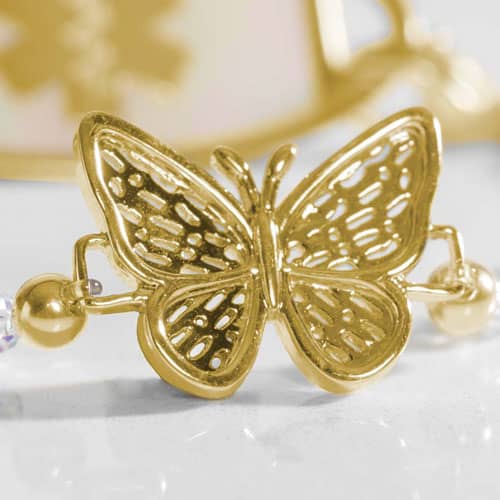 Close-up of a gold butterfly charm on a medical ID bracelet, showcasing intricate filigree detailing and elegant jewelry-inspired design.