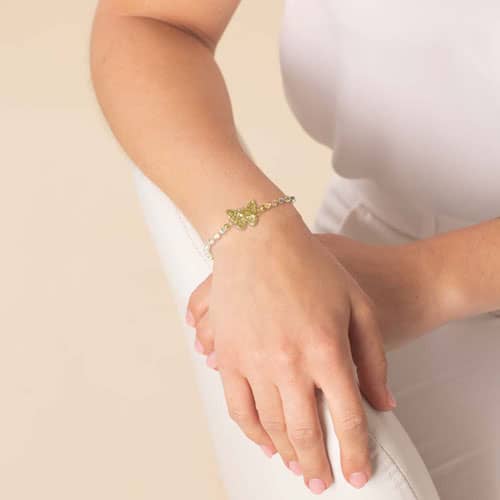 Woman wearing a butterfly medical ID bracelet featuring pearlized beads and gold-tone accents, combining elegant style with safety.