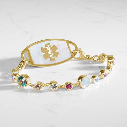 Angled view of the Mia Gold bracelet paired with a medical ID tag, showcasing colorful bezel-set crystals and luminous opal accents.