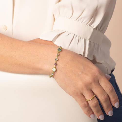 Woman wearing the Mia Gold bracelet featuring colorful bezel-set crystals and luminous opal accents in an elegant interchangeable design.