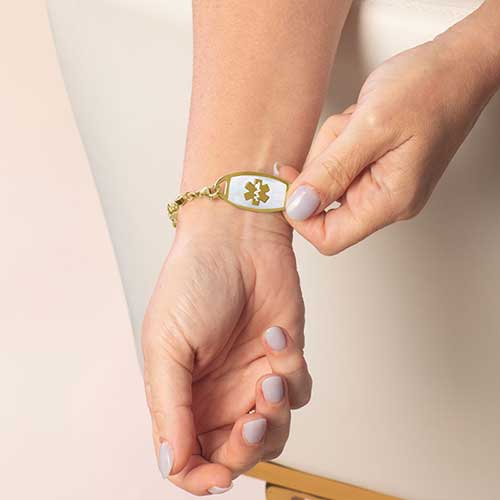 Model showing the front of a medical ID bracelet featuring a mother of pearl  inlay and medical alert symbol paired with the Mia Gold bracelet.