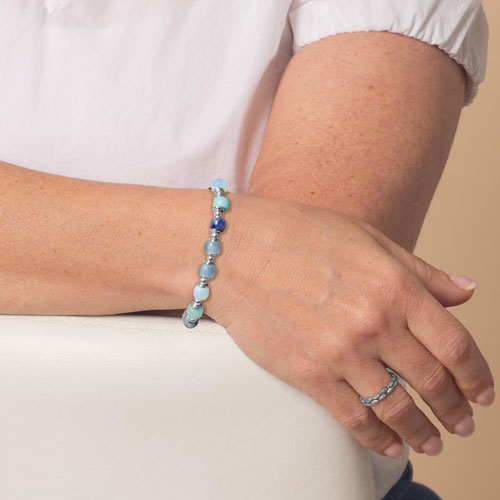 Woman modeling the Selene interchangeable bracelet with blue and aqua beads, designed to pair with medical ID tags.